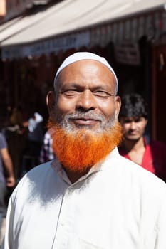 New Delhi, India - November 13, 2011:  proud indian man with red colored beard in traditional clothes at the market poses for a portrait..