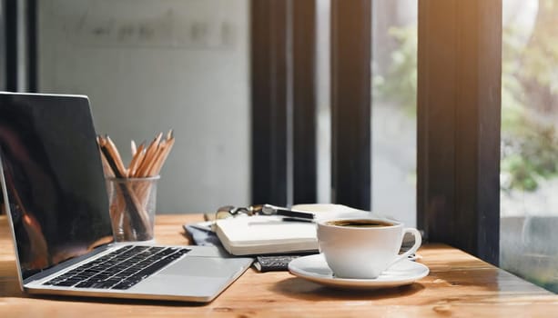 Modern workplace with laptop computer, coffee cup and office supplies