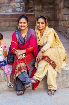 New Delhi, India - November 13, 2011:  indian tourists in colorful festival dress visit the minaret Qutub Minar in New Delhi, the worlds tallest brick minaret with 72 meters.