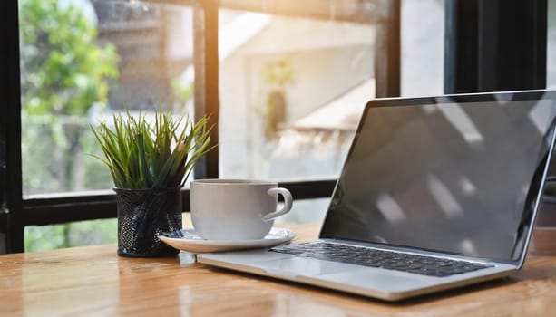 Modern workplace with laptop computer, coffee cup and office supplies