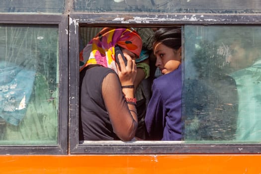 New Delhi, India - November 12, 2011:  indian women in a bus using the mobile and talking.