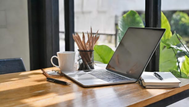 Modern workplace with laptop computer, coffee cup and office supplies