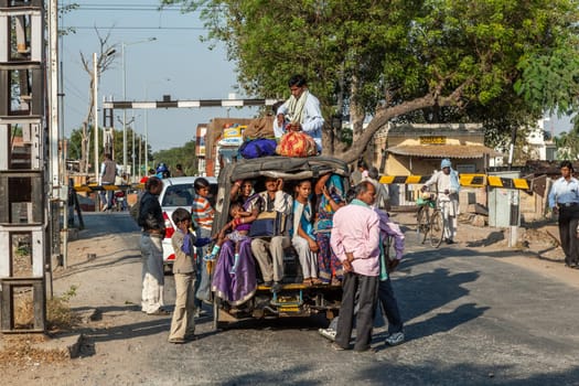Fathepur Sikri, India - November 16, 2011: people in an overloaded Mini bus or rickshaw waiting in a queue for the passing train..