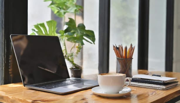 Modern workplace with laptop computer, coffee cup and office supplies