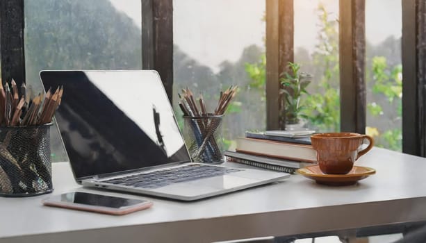 Modern workplace with laptop computer, coffee cup and office supplies