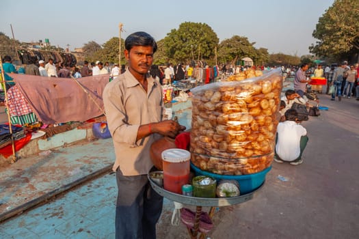 Delhi, India - November 17, 2011: street hawker  sells sweet sugar drinks and prepared potatoes at his bike to the people