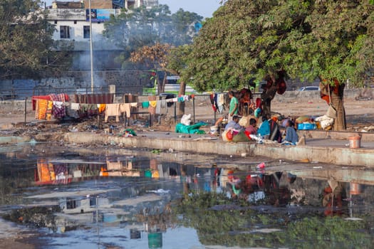 Delhi, India - November 17, 2011: poor homeless families live at the Meena Bazaar in area Chandni Chowk in New Delhi, India at a dirty water basin.