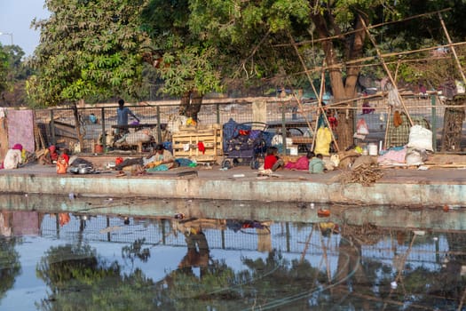 Delhi, India - November 17, 2011: poor homeless families live at the Meena Bazaar in area Chandni Chowk in New Delhi, India at a dirty water basin.
