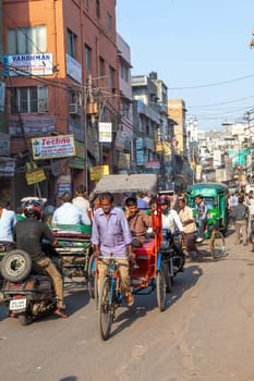 New Delhi, India - November 17, 2011: streetlife at oldest market Chandni Chowk in old Delhi. rickshaw driver transports passenger with his bicycle rickshaw.