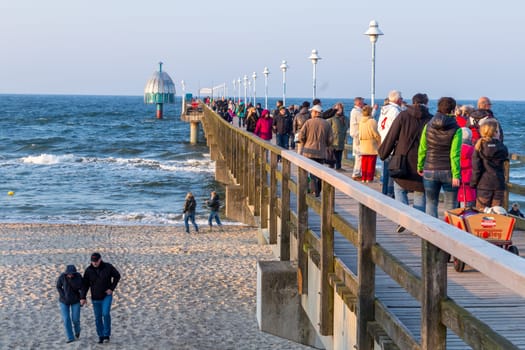 Zinnowitz, Germany - April 19, 2014: people enjoy walking at the beach and on the wooden pier in Zinnowitz, Germany.