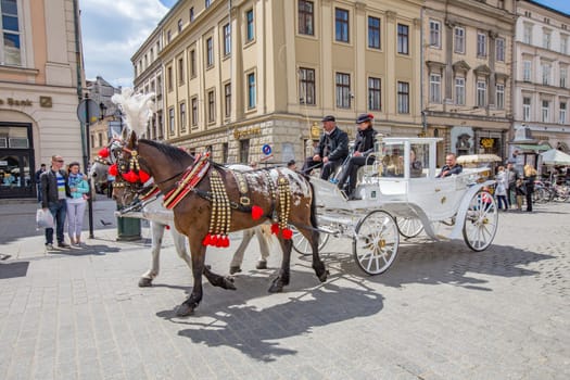 Krakow, Poland - May 4, 2014: Horse-drawn carriage at the Market Square, standardized the color, total length of no more than 7.0 m, can be harnessed to a max of two horses in Krakow, Poland.
