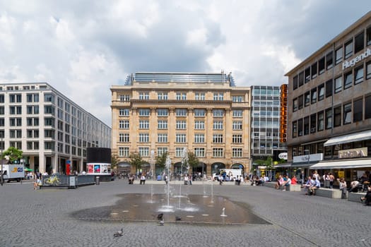 Frankfurt, Germany - June 3, 2014: people relax at the Goethe square downtown Frankfurt with fountain and historic and modern buildings.
