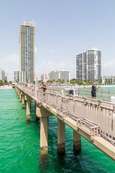 Sunny Isles Beach, USA - August 17, 2014: people at pier on Jade beach in Sunny Isles Beach, USA. Jade Beach and Ocean were completed in 2009 with a elevation of 549 feet located at 170th Street.