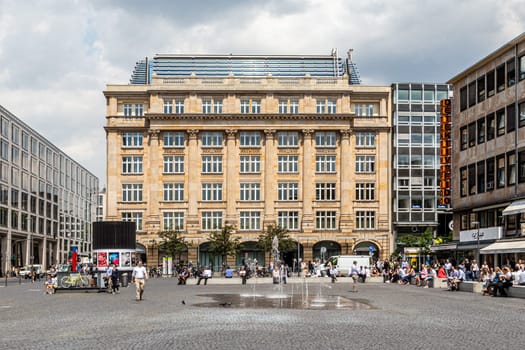 Frankfurt, Germany - June 3, 2014: people relax at the Goethe square downtown Frankfurt with fountain and historic and modern buildings.