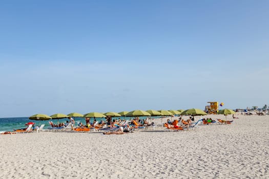 Miami, USA - August 18, 2014: People at the sea side in Miami, USA. Miami Beach is a popular destination among tourists, spiking during the winter time.