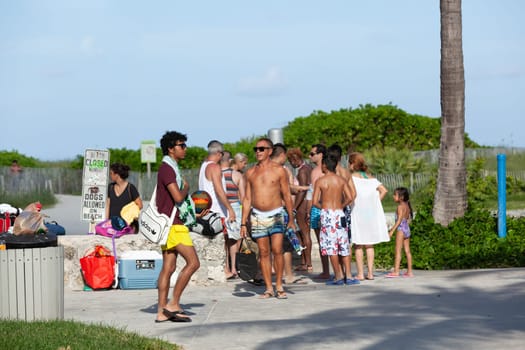 Miami, USA - August 23, 2014: people at south beach walk to ocean drive promenade in late afternoon.