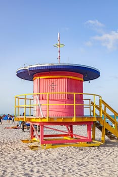 Miami, USA - August 30, 2014: people enjoy south beach in Miami Beach and sit in front of the colorful lifeguard towers.