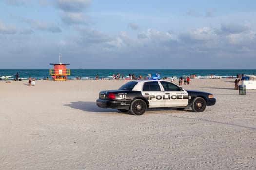 Miami, USA - August 30, 2014: police pays attention at famous south beach sunset in Miami Beach with lifeguard tower in background.