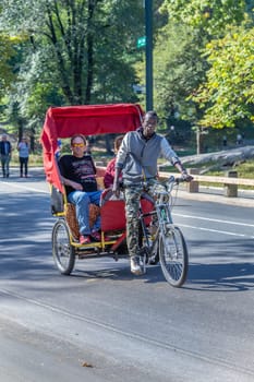 New York, USA - October 21, 2015:  rickshaw driver by bicycle at central park in New York with passengers, USA.