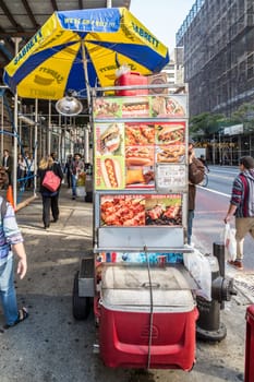 New York, USA - October 21, 2015: street view with mobile food vendor stall downtown New York. The vendor offers different kind of grilled or cooked meat.