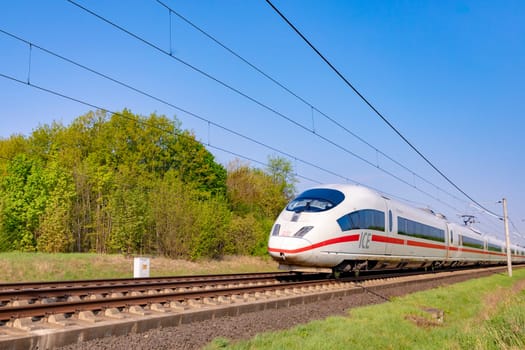 Raunheim, Germany - April 21, 2018: german high speed train Intercity Express (ICE) train of Deutsche Bahn passes rural landscape near Raunheim. ICE 3 class train is manufactured by Siemens.