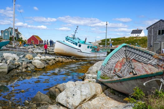 Peggys Cove, Canada - September 9, 2018: old rotten wooden fishermens boats are at the beach of village Peggys Cove in Kanada at the pascific ocean.