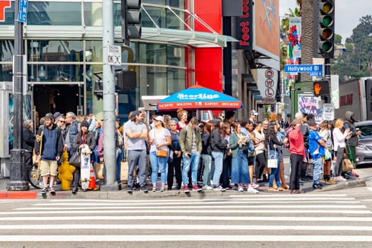 Los Angeles, USA - March 5, 2019: people at a pedestrian crossing wait for green light on Hollywood boulevard of Walk of Fame.