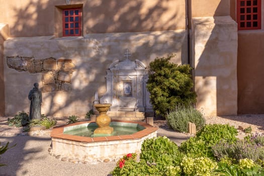 Carmel, USA - March 15, 2019:  Patio view with statue and fountain of Mission San Carlos Borromeo de Carmelo, a Roman Catholic Chapel in Carmel by the Sea, California, USA.
