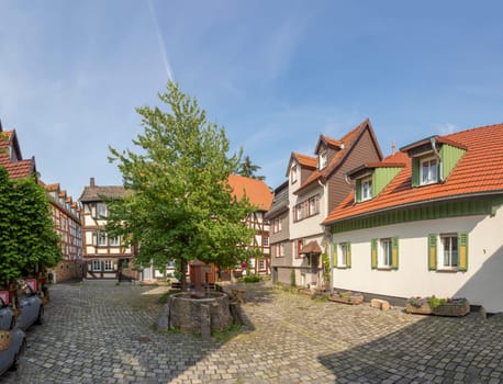 Alsfeld, Germany - June 25, 2021: half timbered historic houses at central square with tree in Alsfeld, germany.