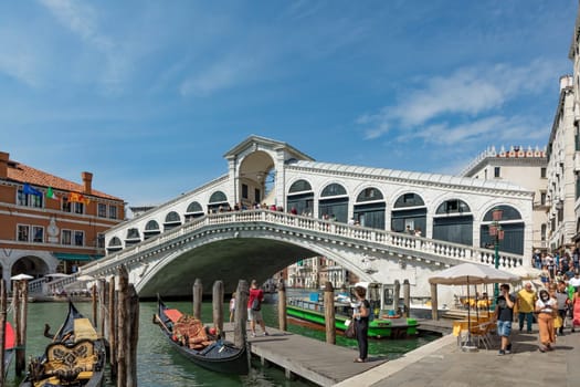 Venice, Italy - July 3, 2021: view to Rialto bridge at grand canal in Venice, Italy with boats and tourists watching the canal.