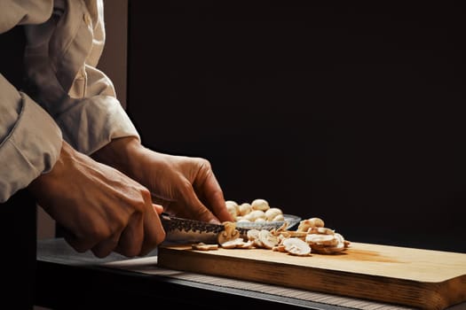Hands of a woman cutting champignon mushrooms into thin slices