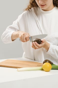 Unrecognizable woman cutting fresh avocado into halves. Concept of balanced eating.