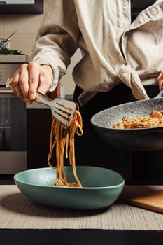 Unrecognizable woman serving rice noodles with vegetables and beef from frying pan into plate