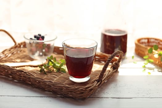 Grape juice poured into a glass on a rattan tray