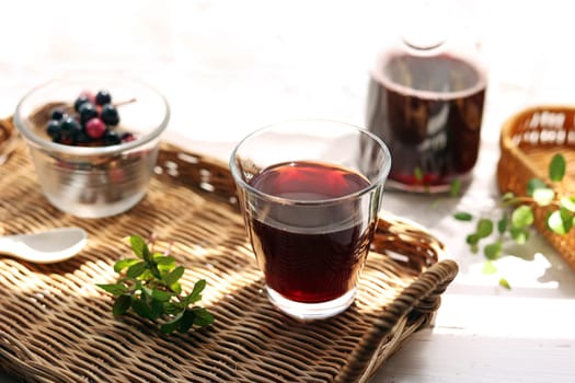 Grape juice poured into a glass on a rattan tray