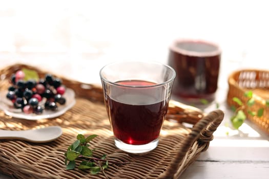 Grape juice poured into a glass on a rattan tray