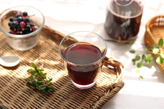 Grape juice poured into a glass on a rattan tray