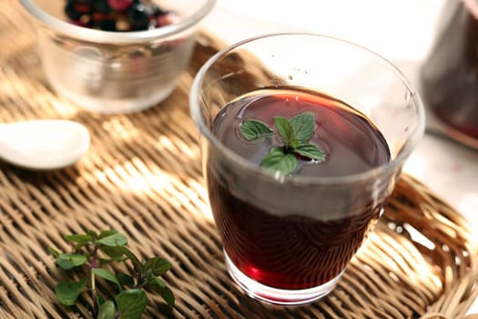 Grape juice poured into a glass on a rattan tray