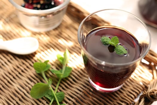 Grape juice poured into a glass on a rattan tray