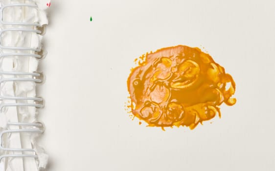 Orange paint swatch on a sheet of white paper in a notepad, close up