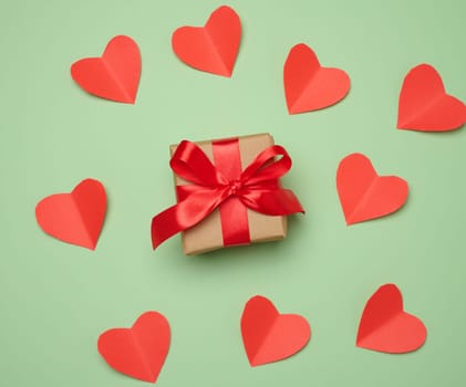 Gift box with red satin ribbon and bow on a green background.Holiday background, top view