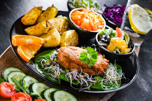 Pulled chicken cutlet coated with breadcrumbs with potatoes and vegetable salads