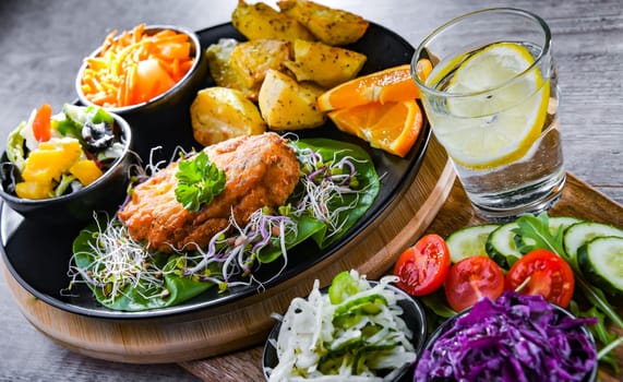 Pulled chicken cutlet coated with breadcrumbs with potatoes and vegetable salads