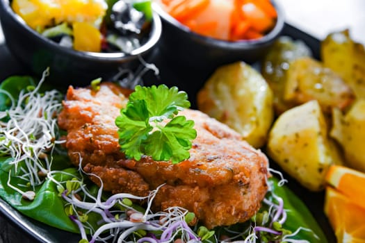 Pulled chicken cutlet coated with breadcrumbs with potatoes and vegetable salads