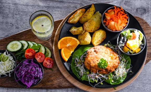 Pulled chicken cutlet coated with breadcrumbs with potatoes and vegetable salads