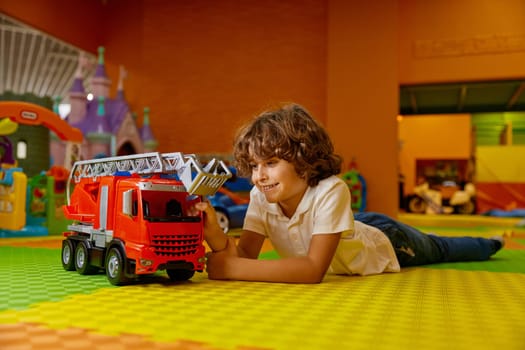 Boy child playing vehicle toys at kids care center. Carefree male kid enjoying happy time at game room