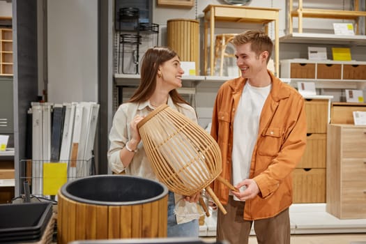 Cheerful man and woman couple deciding to buy craft furniture for home or garden at shop store department. Shopping together