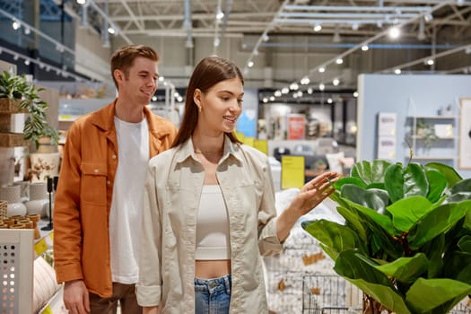 Happy man and woman couple walking through store racks with goods for design interior and decoration. Family shopping time on holidays vacation