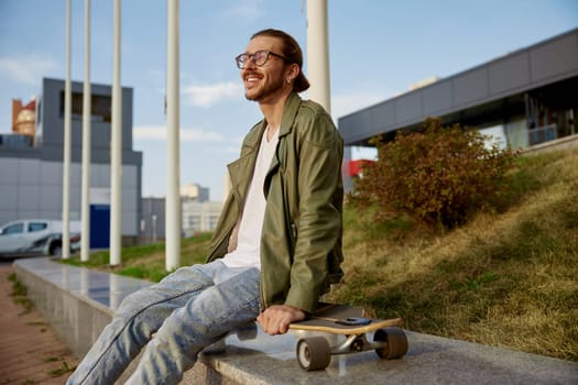 Young hipster sporty man with skateboard rest after training race in skate board park. Summer outdoor recreation time for active young people