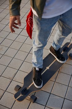 Closeup hipster man riding skateboard. Focus on foot wearing sneakers with view from top. Leisure activity and extreme sports concept